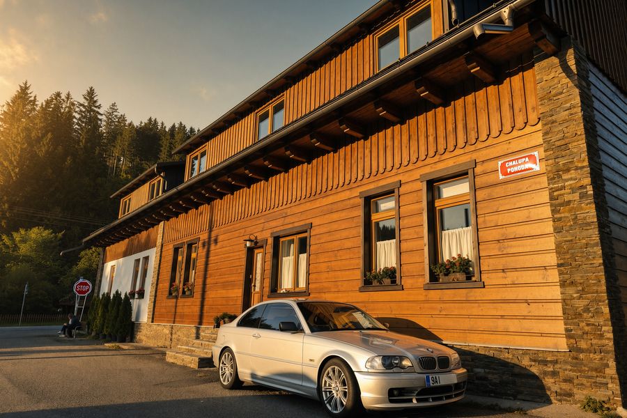 Front of the cottage in the evening sun, wooden facade with geraniums and parking by the house