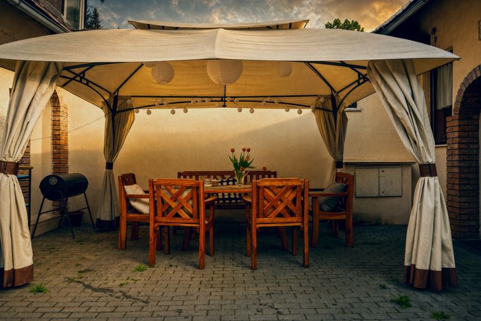Venkovní terasa se stolem a židlemi pod markýzou